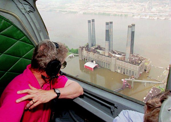 Former U.S. President Bill Clinton looks at a flooded power plant near St. Louis, Missouri, on July 17, 1993